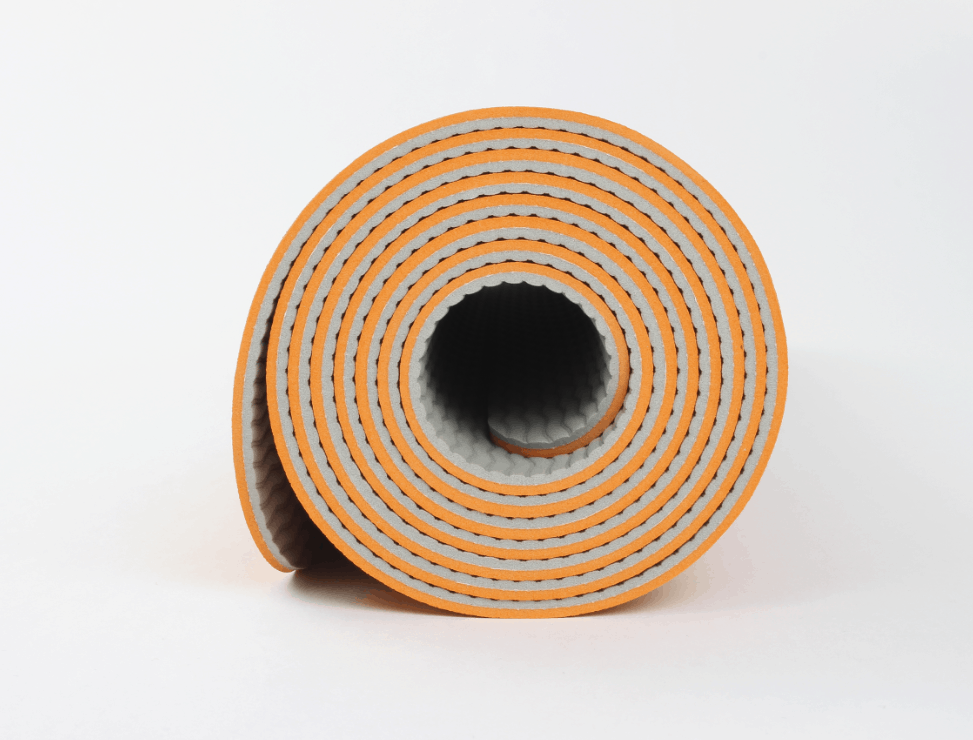 Rolled yoga mat in orange – textured grip surface for stability during workouts