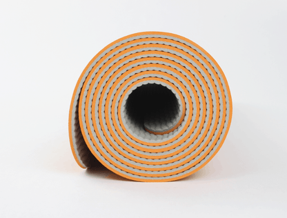 Rolled yoga mat in orange – textured grip surface for stability during workouts