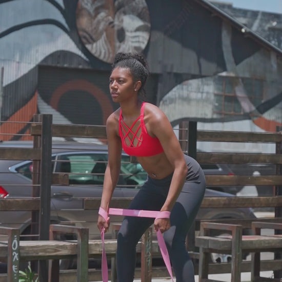 Side view of outdoor resistance band walk – controlled lower-body movement using long elastic band for glute and hip activation