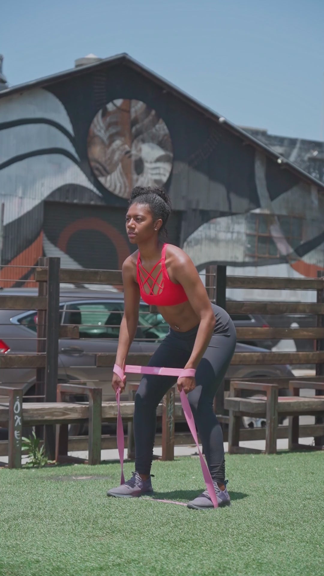Side view of outdoor resistance band walk – controlled lower-body movement using long elastic band for glute and hip activation