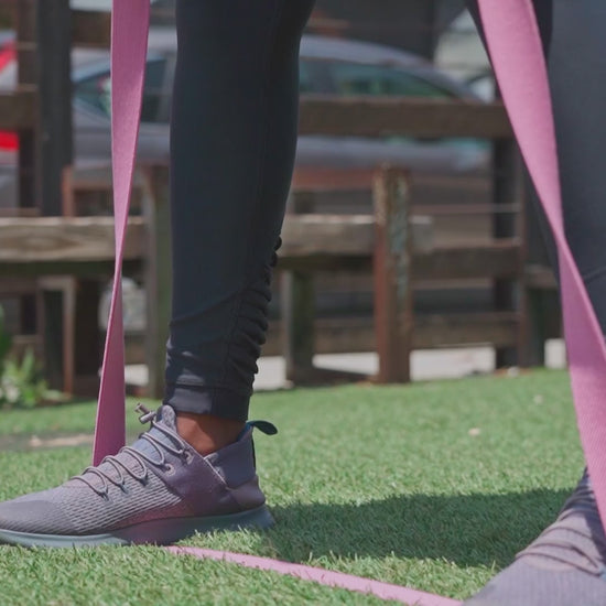 Person performing resistance band walk outdoors – gentle lower-body workout using long elastic bands for glute activation and mobility training