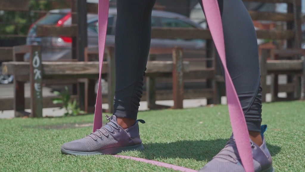 Person performing resistance band walk outdoors – gentle lower-body workout using long elastic bands for glute activation and mobility training