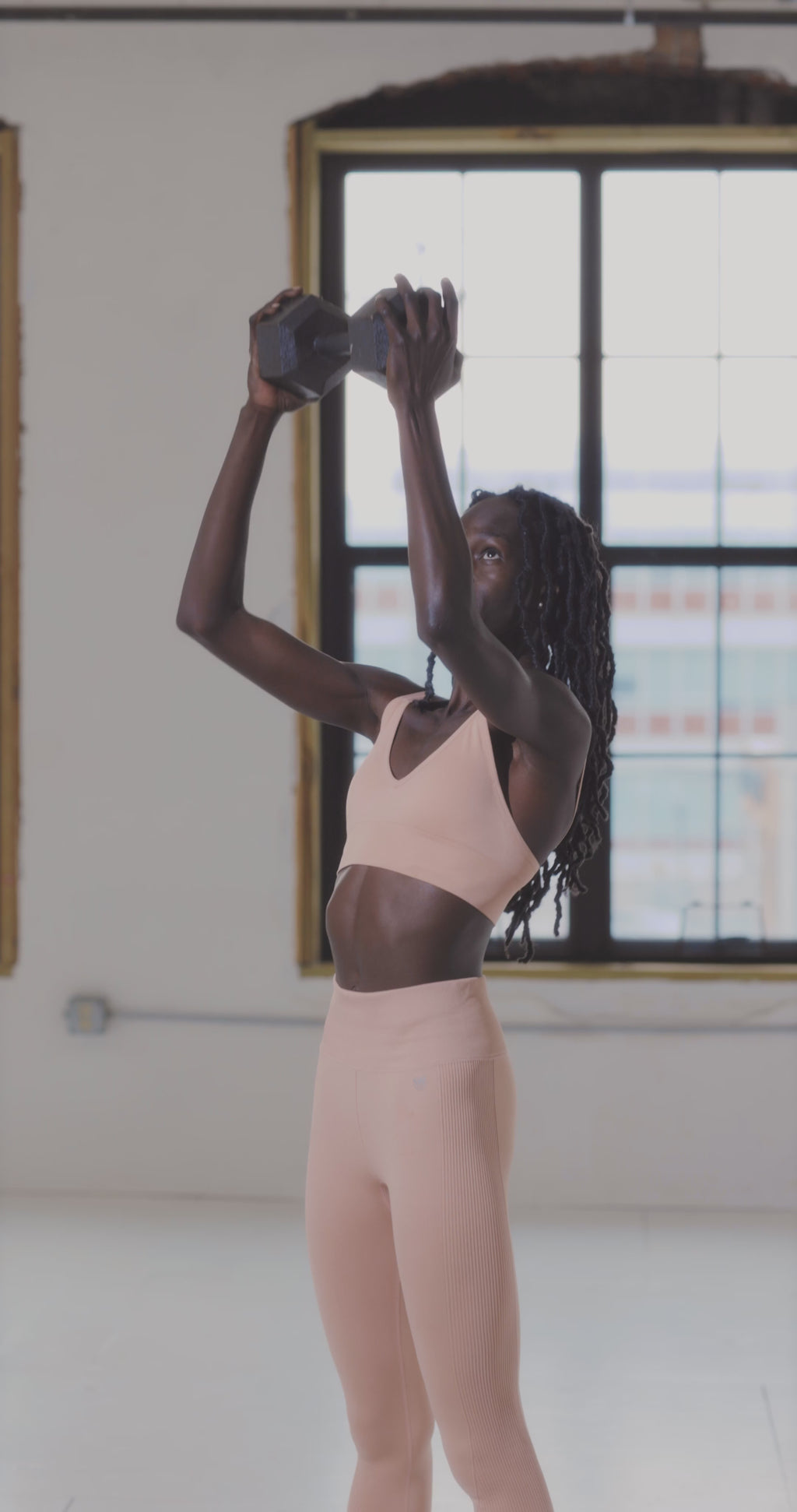 Woman lifting hex dumbbell during controlled home workout – gentle strength for upper body